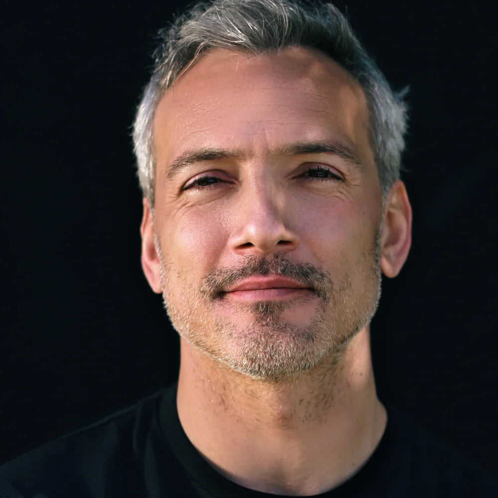 Porträt eines selbstbewussten Mannes mit grauem Haar vor dunklem Hintergrund, Fokus auf natürliche Männerhautpflege