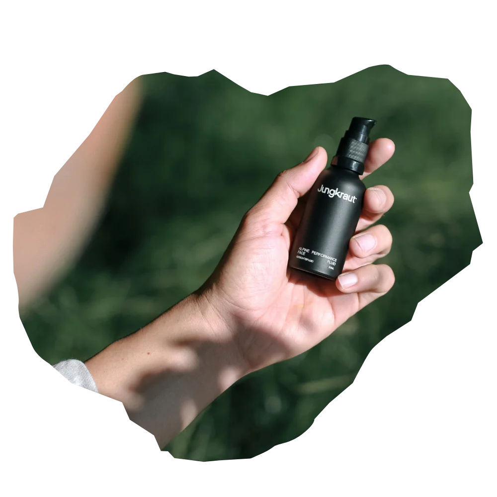 Hand hält schwarzes Jungkraut Gesichtsserum mit Swiss NatureTECH® für Männer vor grünem Naturhintergrund